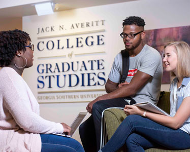 Three students have a conversation in front of a sign for Georgia Southern's Jack N. Averitt College of Graduate Studies