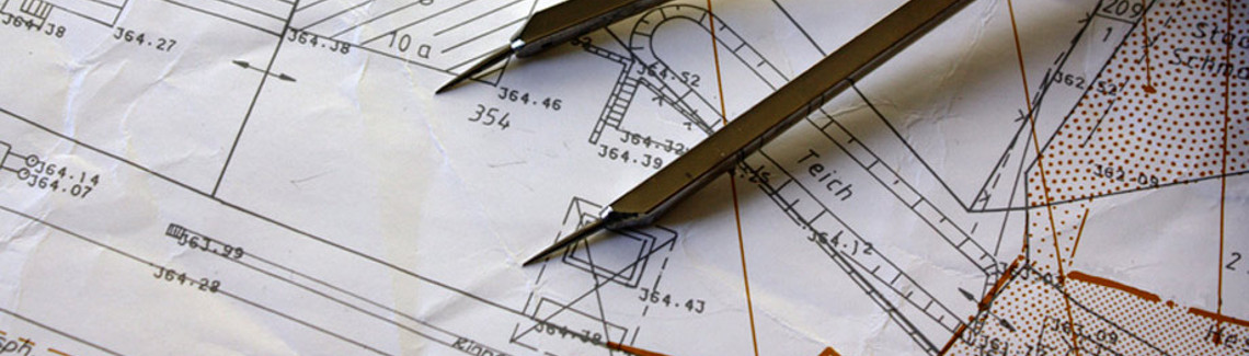Architectural blueprint with metal compass on top, showing elevation lines, labels, and technical markings.