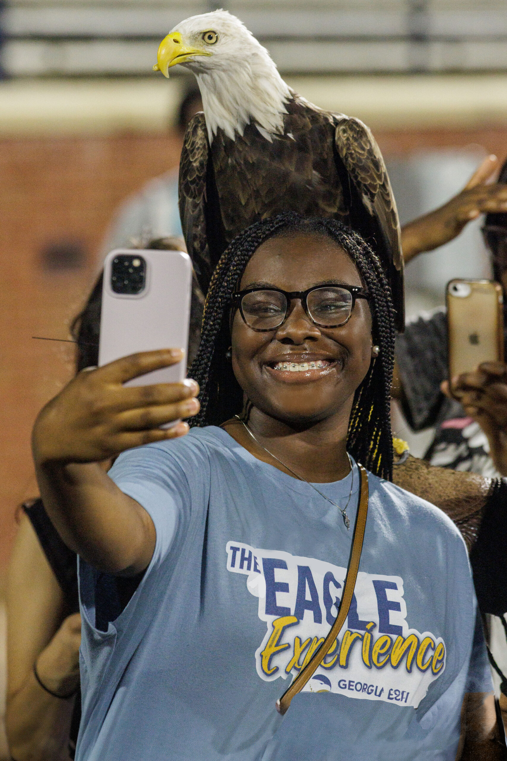 Freshman minority student takes a selfie with Georgia Southern Eagle posed on head.