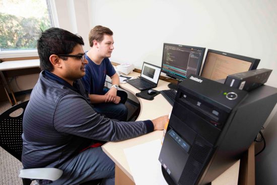 Two students working at a computer lab station together on information technology.