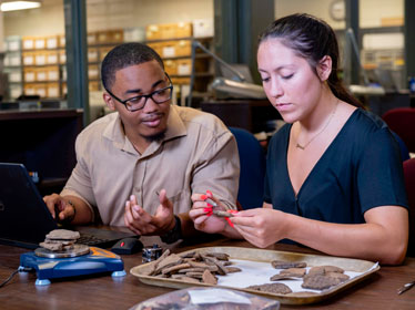 Two Georgia Southern Department of Sociology and Anthropology students assess and catalog artifacts in an on-campus lab
