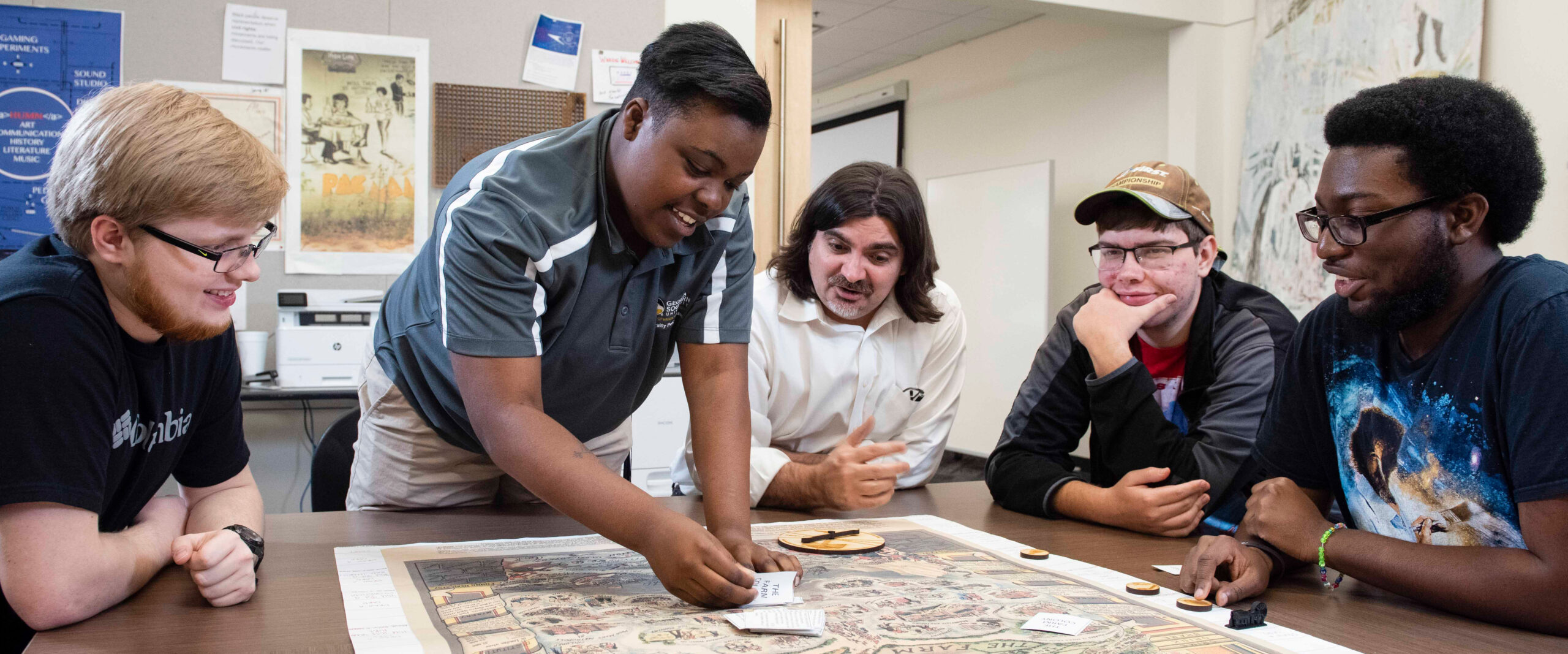 Group of Georgia southern students around a table studying a historical map; hands-on exploration of ancient artifact