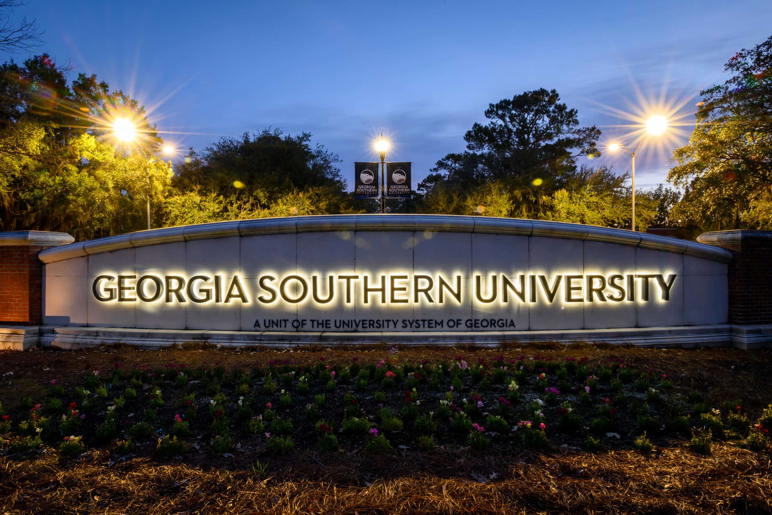 A nighttime photograph of the large, illuminated stone entrance sign for Georgia Southern University, subtitled 