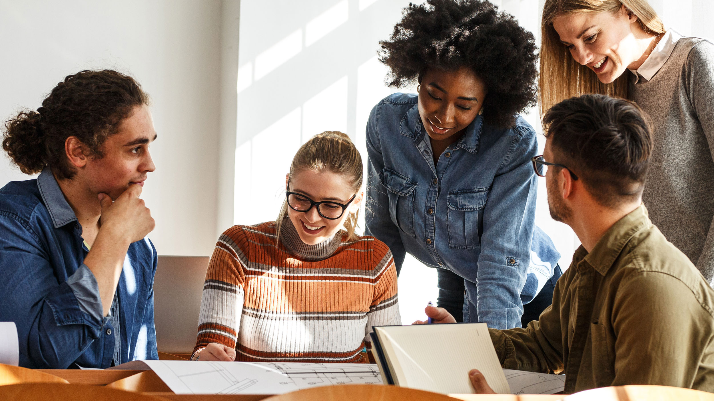 group of georgia southern students collaborating together on master's in english, in well lit common space and educational setting