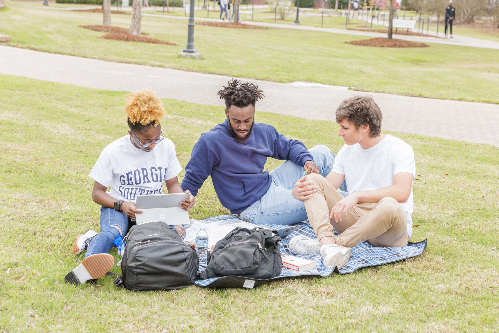A group of Georgia Southern students enjoy the campus green space and study together on a lawn.