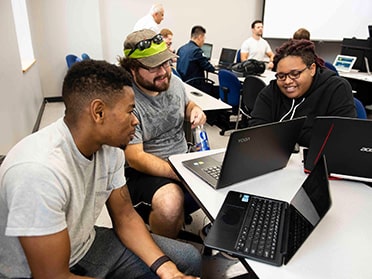 Sitting around a table with laptops, three Georgia Southern B.S. in Computer Science students meet up for a study session