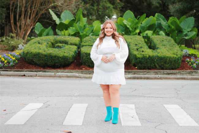 Gracie McMillan stands in a white dress and teal boots in front of the GSU bushes.
Photo Credit: Allie Rose Photography