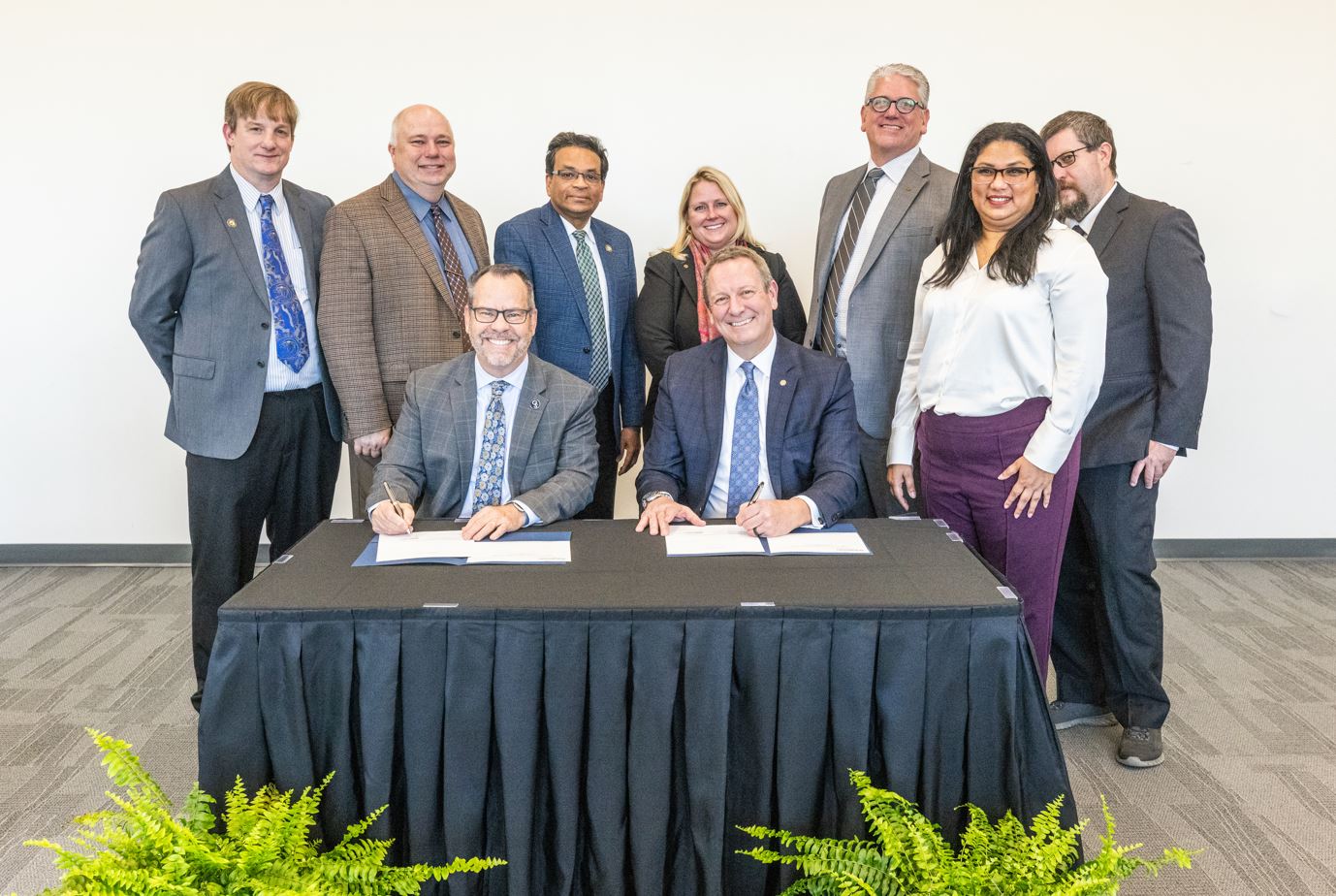 Georgia Southern President Kyle Marrero and Shimadzu President Patrick Fromal sign a memorandum of understanding surrounded by colleagues.