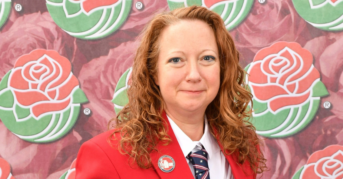 Georgia Southern alumna Joy Harden poses in front of a rose backdrop in a red jacket and striped American flag tie